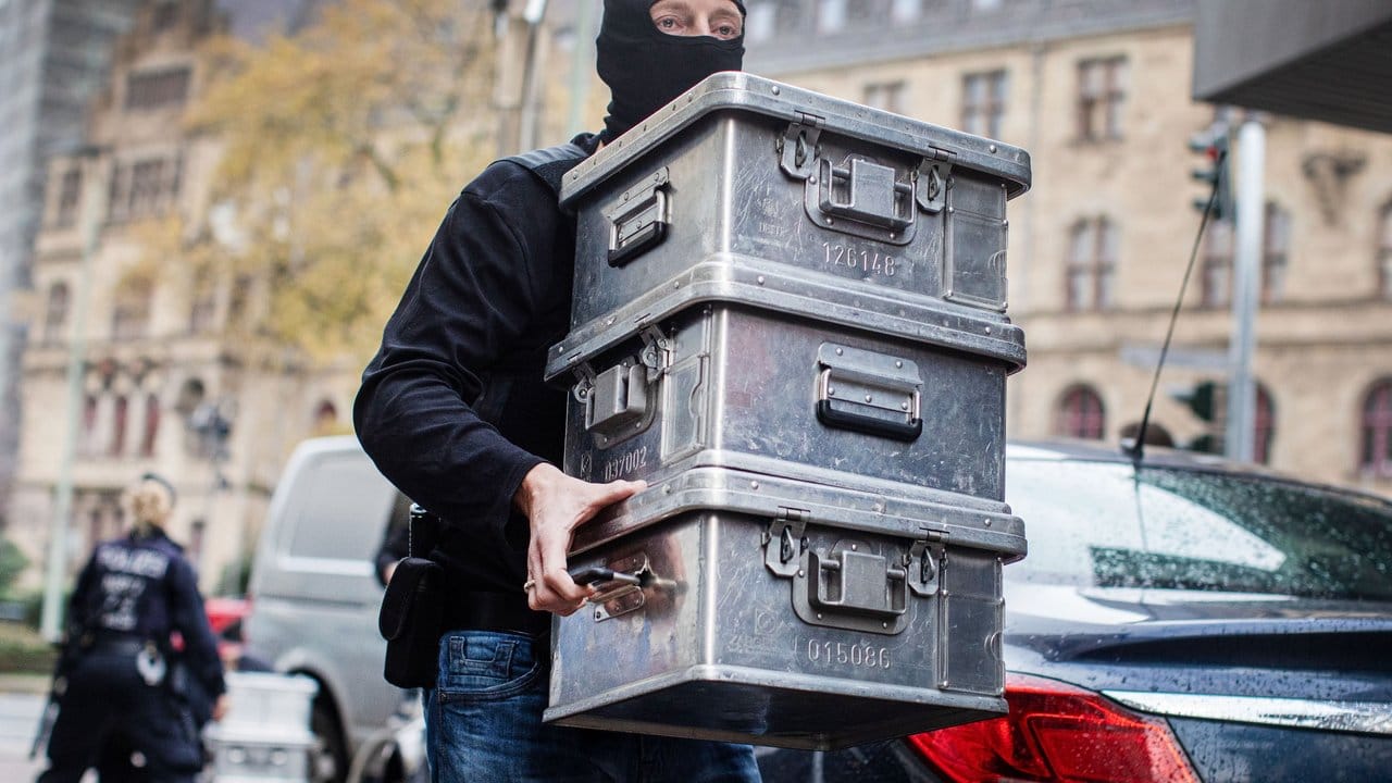 Ein Polizist transportiert Beweismittel ab: "Wir haben einen Fuß in die Tür illegaler Finanzgeschäfte bekommen. Ein Polizist transportiert Beweismittel ab: "Wir haben einen Fuß in die Tür illegaler Finanzgeschäfte bekommen.