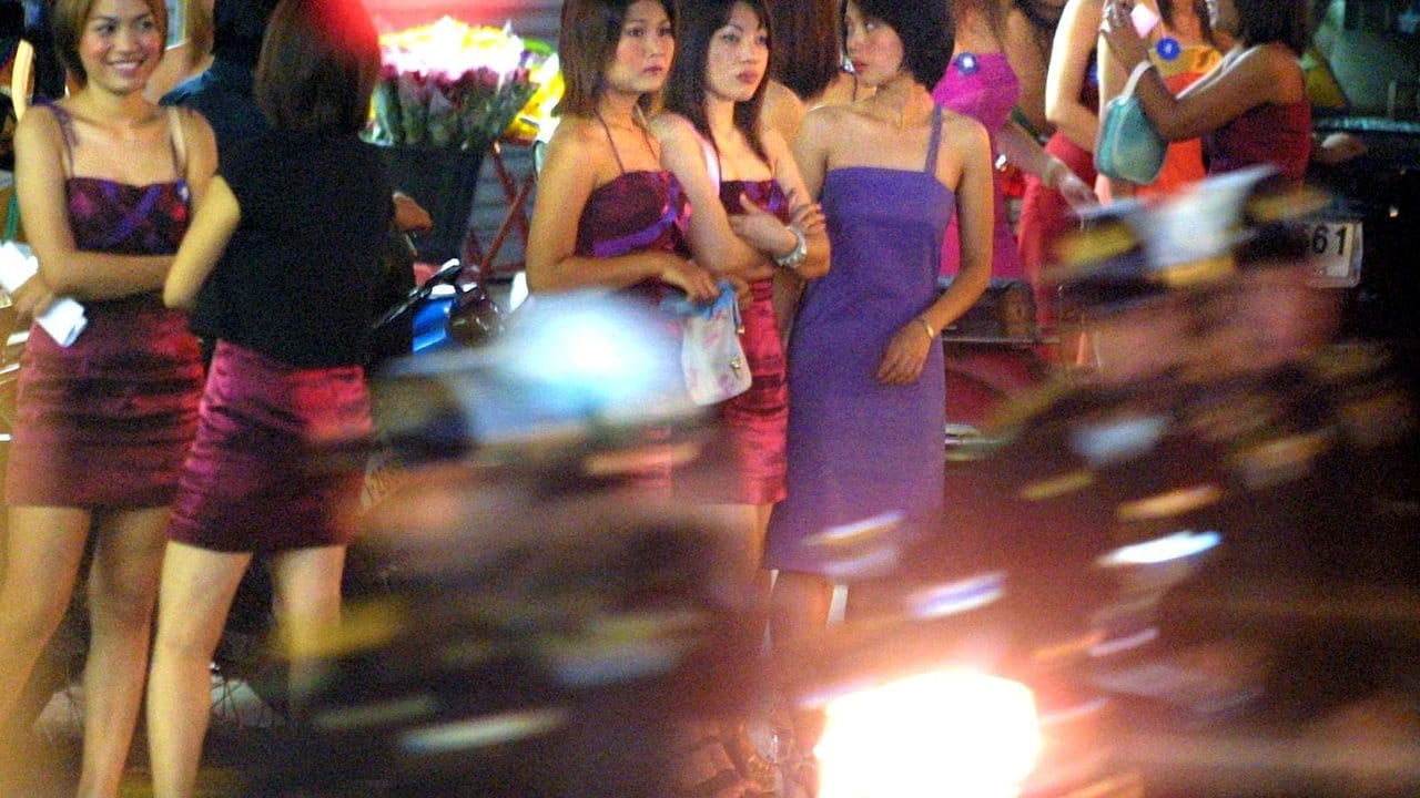 Prostituierte warten in Bangkoks Rotlichtviertel am Straßenrand auf Kundschaft.