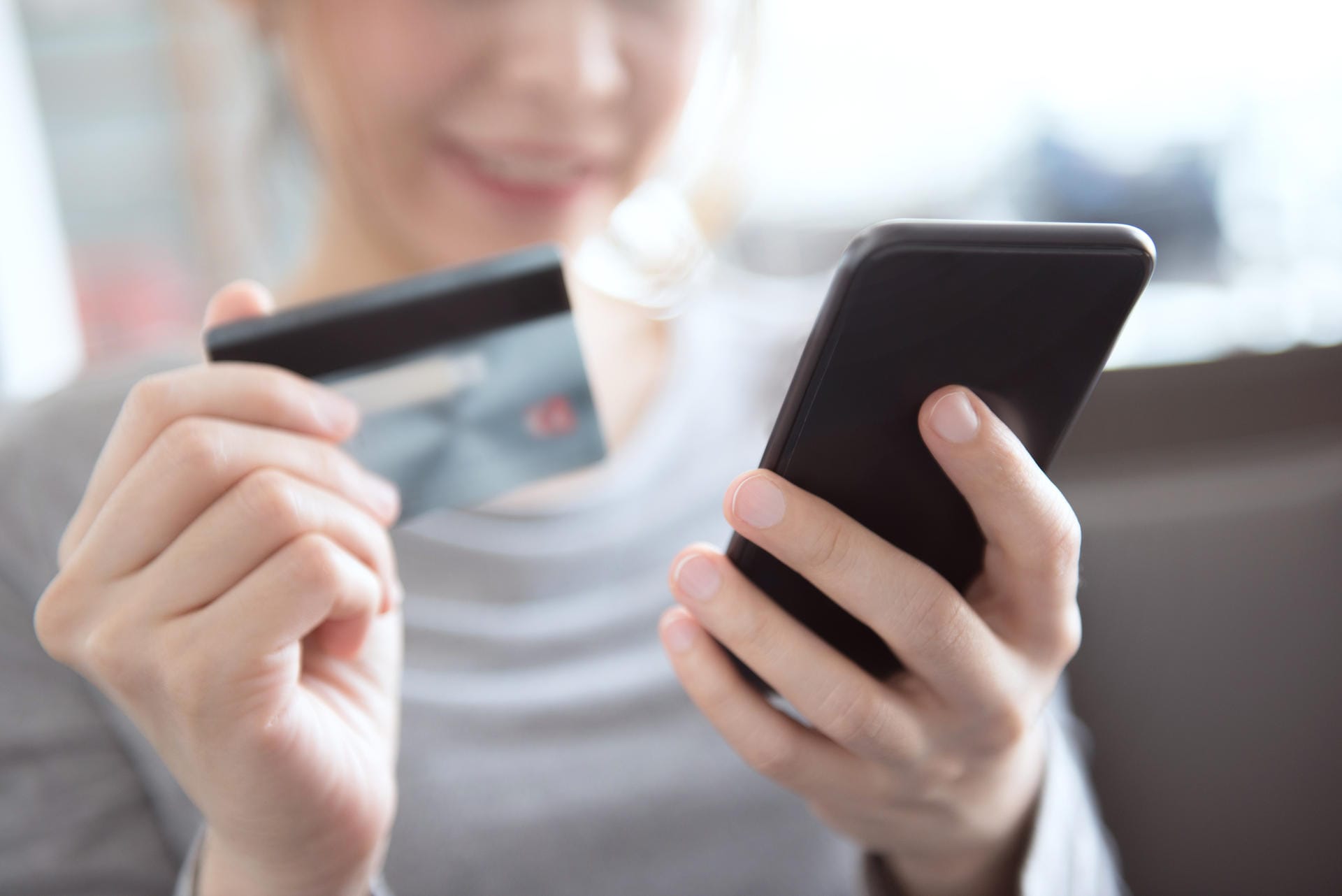 Eine Frau gibt ihre Kreditkartendaten in das Smartphone ein.