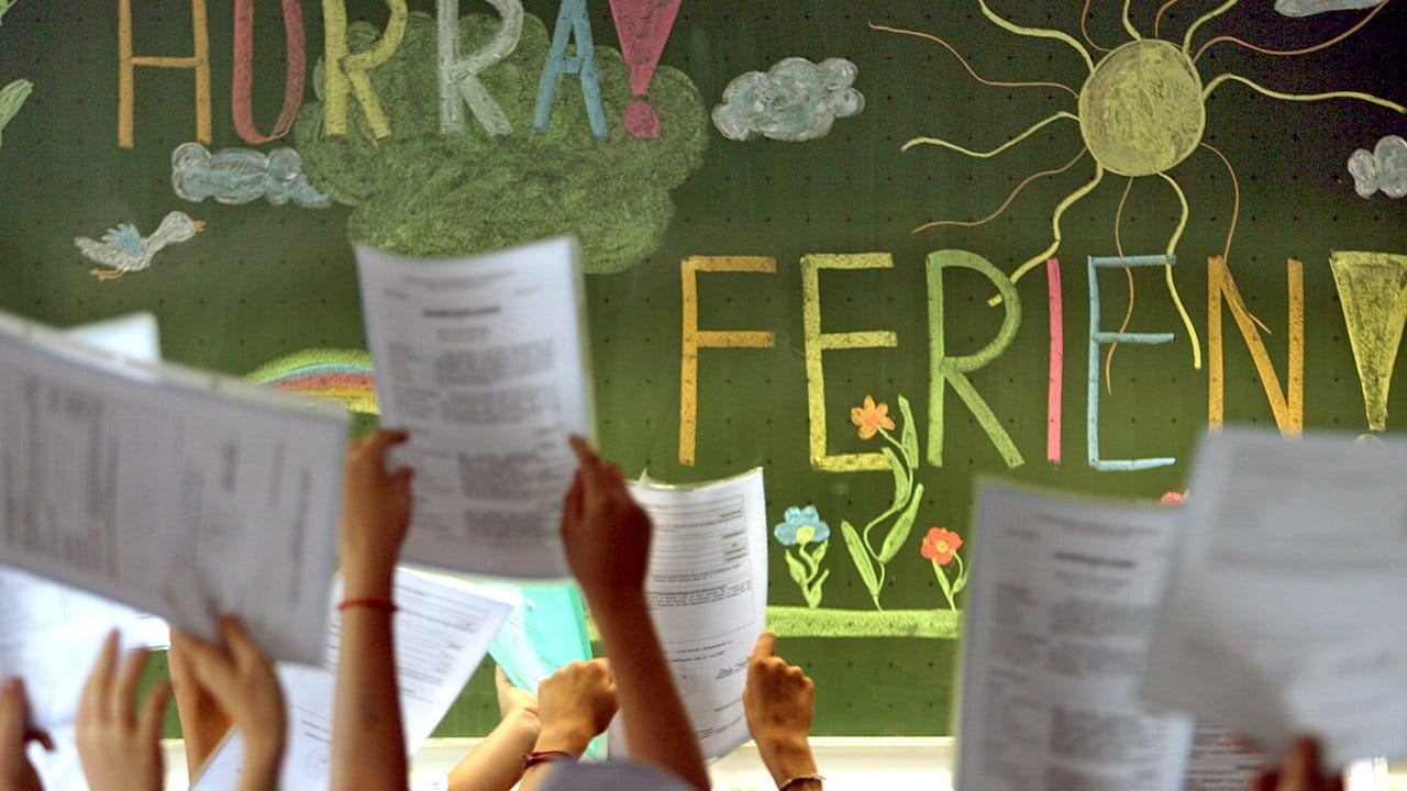 Kinder der vierten Klasse einer Grundschule in Kaufbeuren jubeln vor einer Tafel mit der Aufschrift "Hurra Ferien".