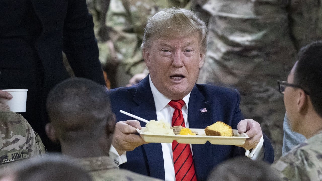 US-Präsident Donald Trump hält bei einem Besuch von amerikanischen Truppen ein Tablett mit Essen in der Hand.