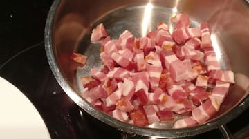 Während das vorbereitete Fleisch eine Stunde zieht, schneiden Sie den Speck kurz vor Ende der Stunde in kleine Stücke und braten Sie diese in einem großen Topf an.