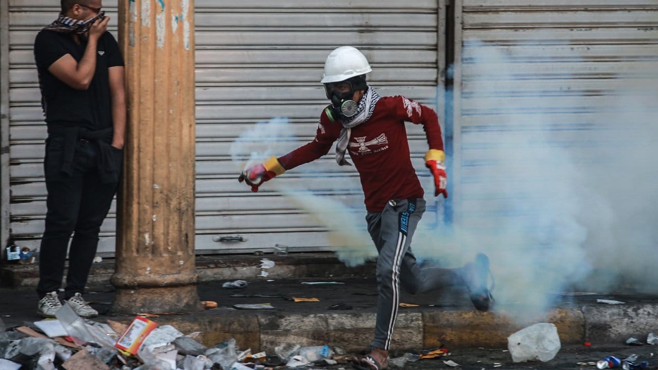 Sprint mit Tränengasgranate: Ein irakischer während eines gewalttätigen Protestes gegen die Regierung in Bagdad.