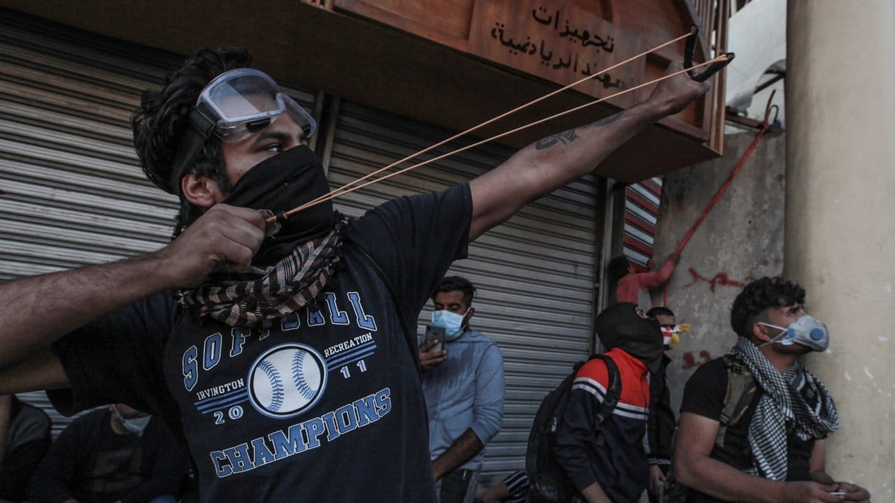 Ein Demonstrant in Bagdad zielt mit einer Steinschleuder auf Einsatzkräfte.