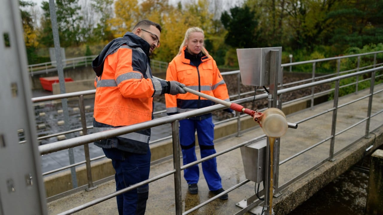 Beim Betriebsdienst sind Fachkräfte für Abwassertechnik auf dem Gelände der Kläranlage unterwegs: Auszubildender David Uweis und Koordinatorin Nadine Wons nehmen eine Wasserprobe.