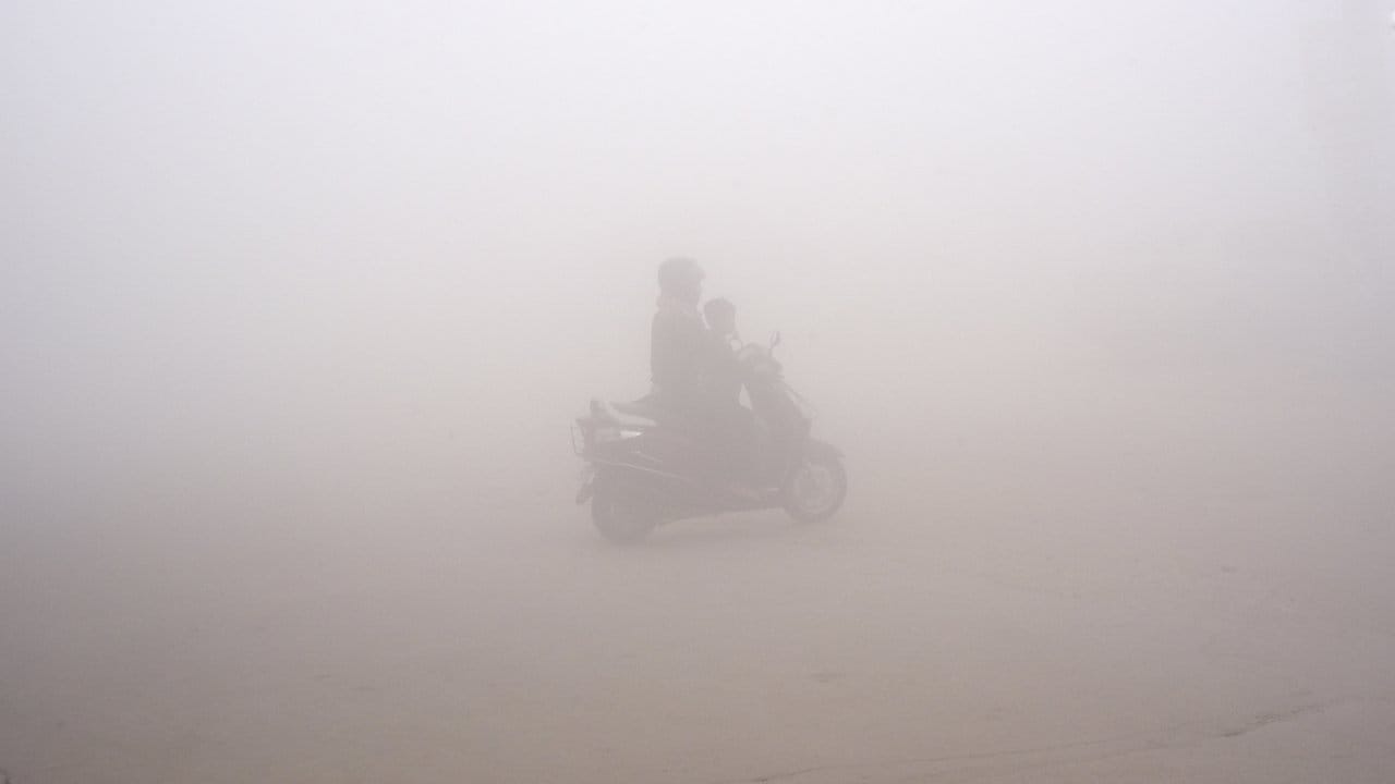Schlechte Luft in Neu Delhi: Eine Frau bringt ihr Kind zur Schule.