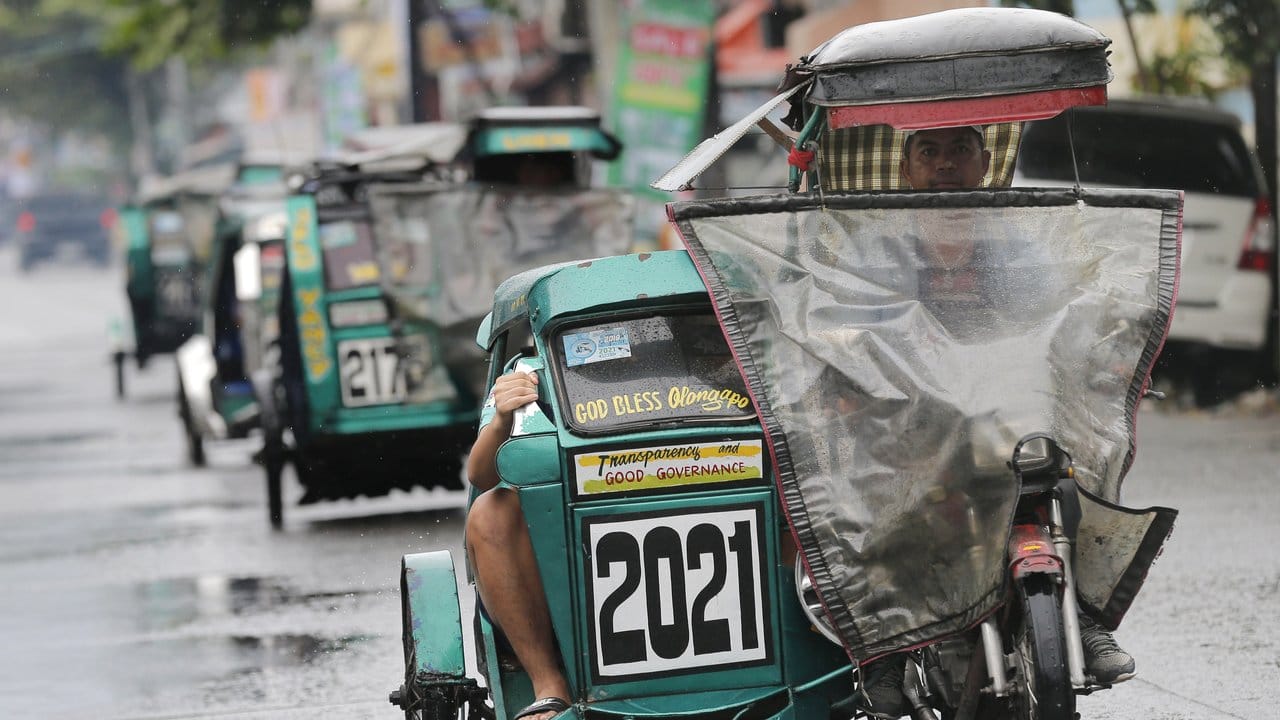 Dreirädrige Mopeds fahren mit Regenschutz durch die Stadt Subic. Dreirädrige Mopeds fahren mit Regenschutz durch die Stadt Subic.