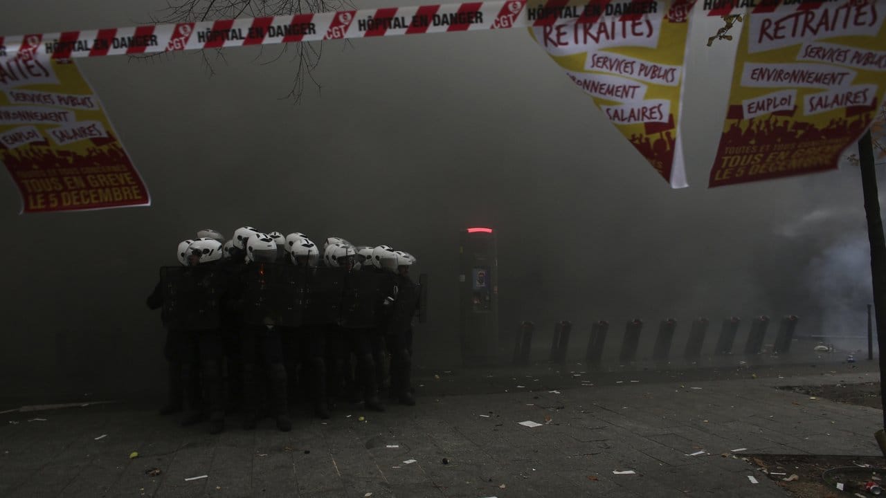 Polizisten formieren sich in Paris inmitten einer dichten Rauchwolke.