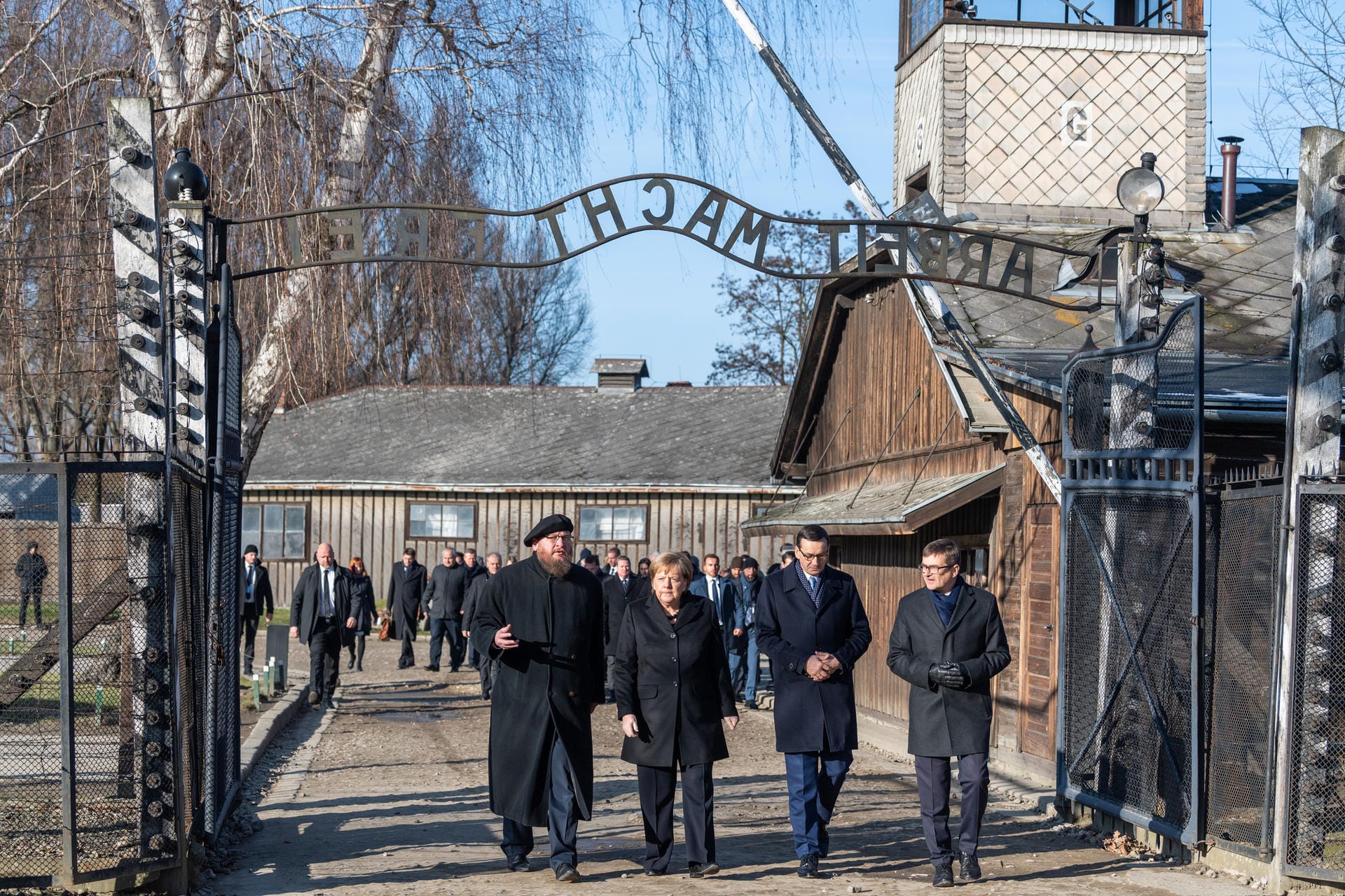 Bundeskanzlerin Angela Merkel und Polens Ministerpräsident Mateusz Morawiecki gehen im einstigen Vernichtungslager Auschwitz durch den Eingang mit der Aufschrift: "Arbeit Macht Frei".