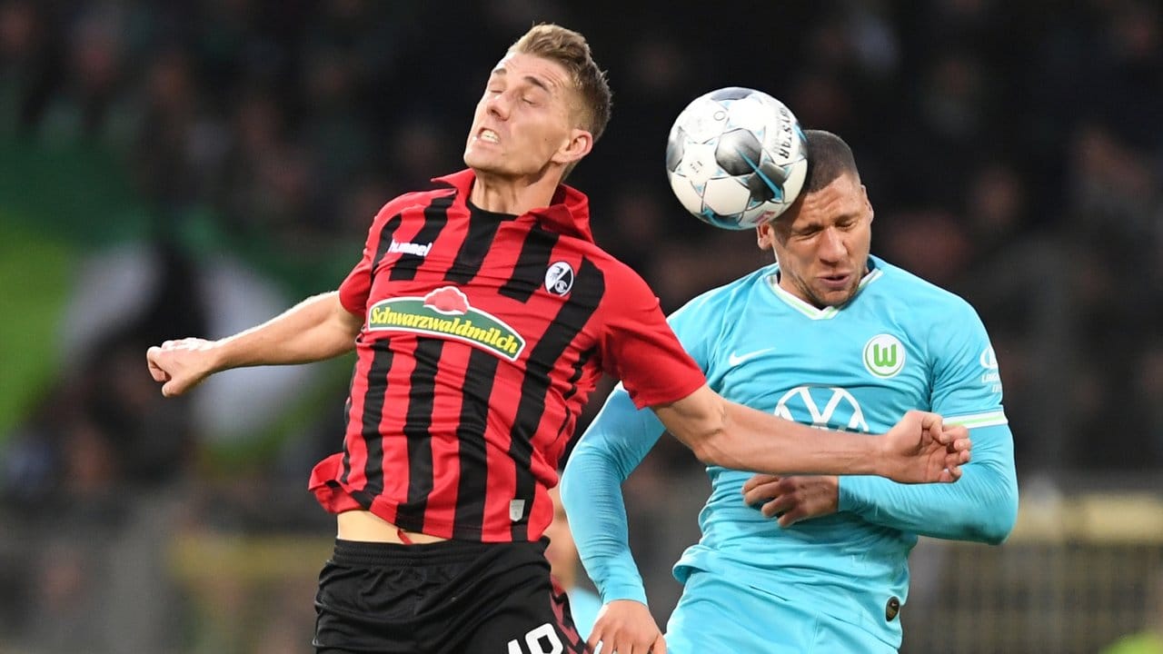 Freiburgs Nils Petersen (l) kämpft mit Wolfsburgs Jeffrey Bruma (r) um den Ball.