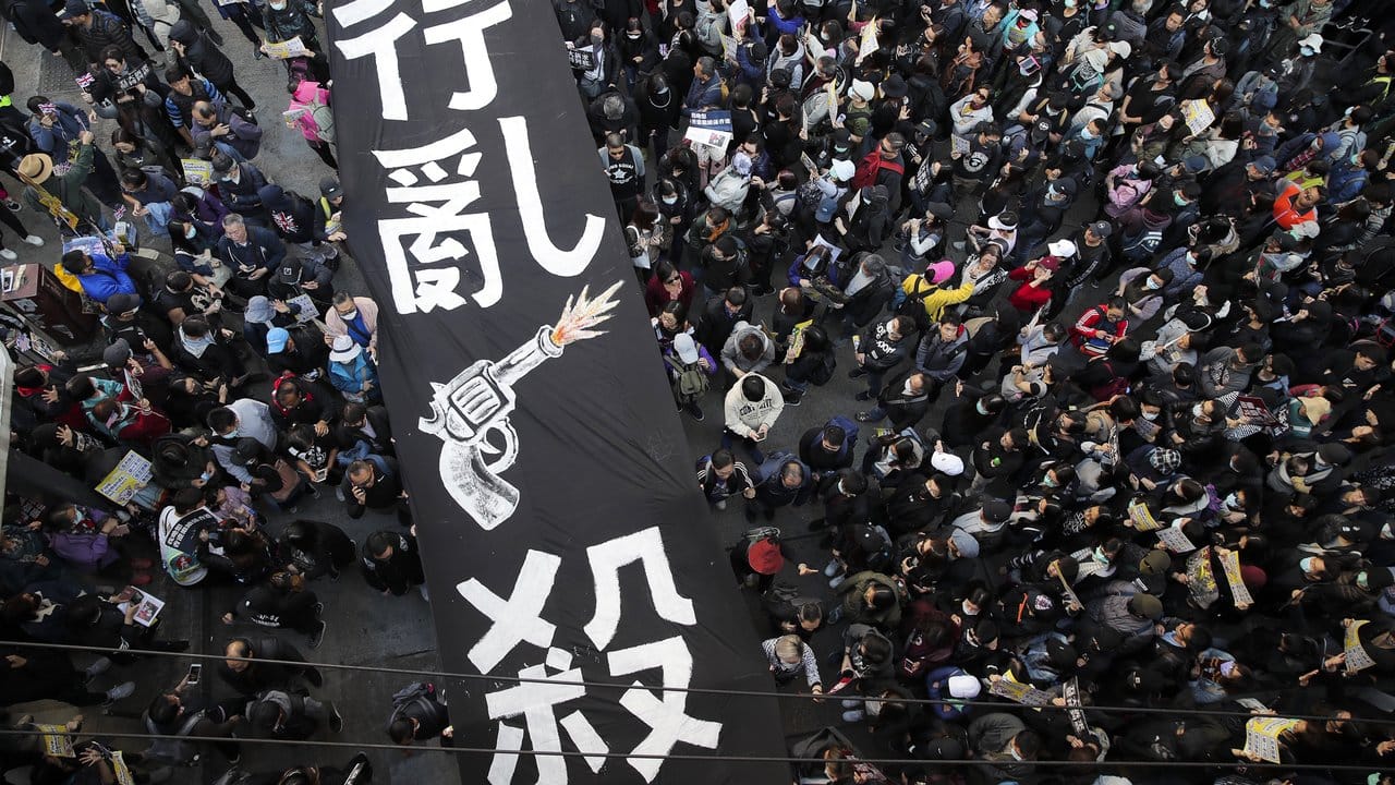 Pro-demokratische Demonstranten marschieren unter einem Banner mit der Aufschrift "Um sich greifendes Töten" steht.