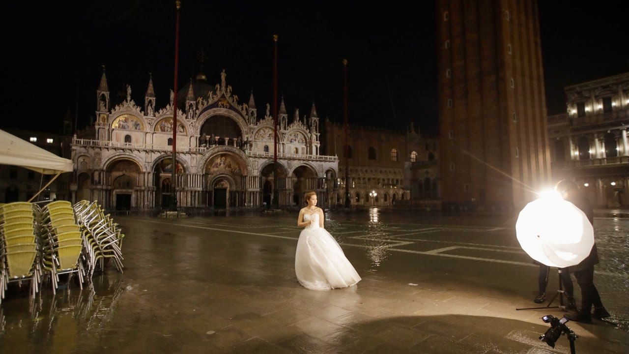 Fototermin: Eine Frau im Brautkleid steht am frühen Morgen auf dem überfluteten Markusplatz in Venedig.