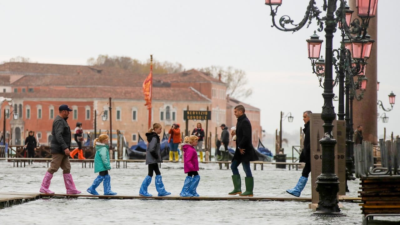 Hochwasser-Routine in Venedig: Touristen sind auf schmalen Stegen unterwegs.