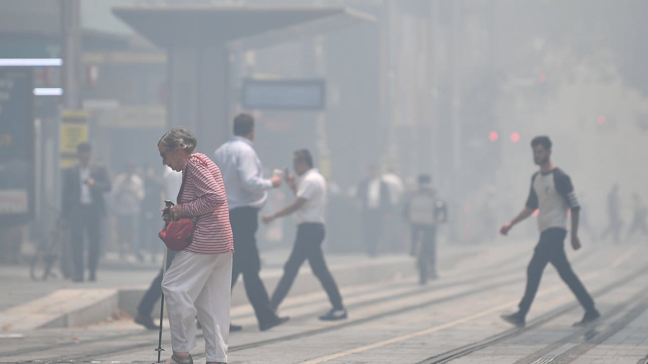 Fußgänger überqueren die in Rauch gehüllte George Street im Stadtzentrum von Sydney.