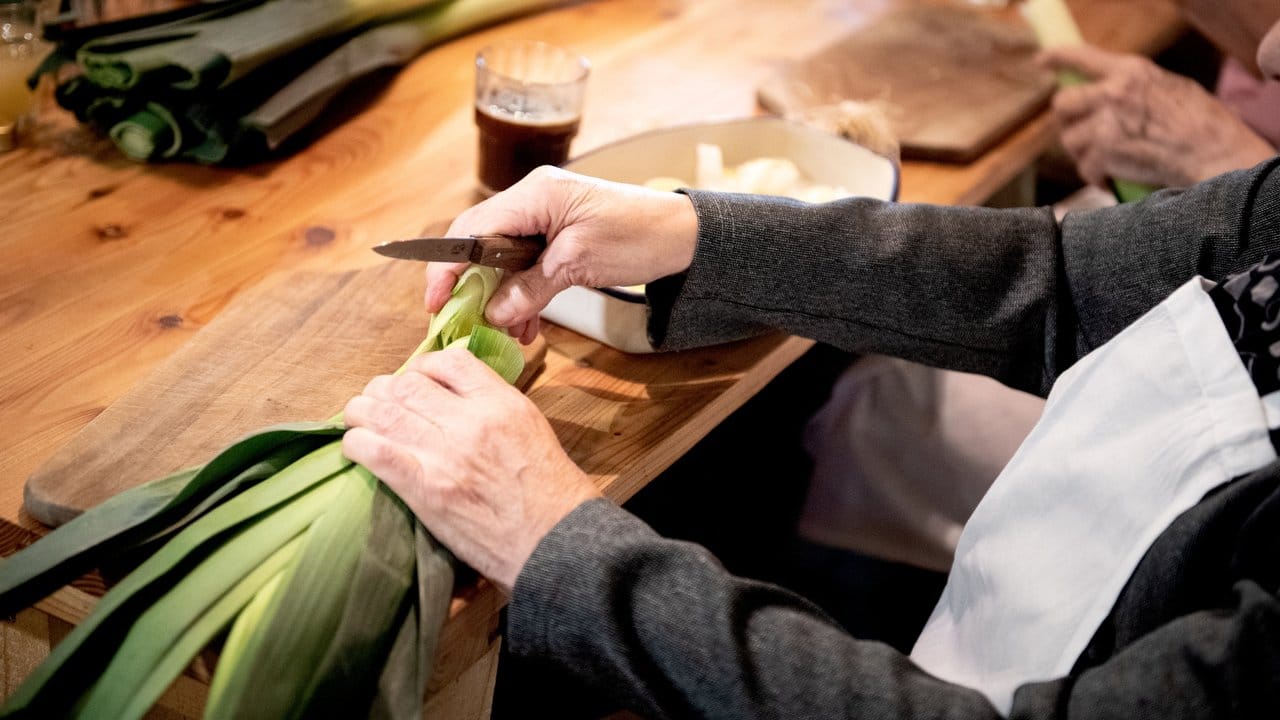 Um die Funzelsuppe aus dem Kochbuch "Unser kulinarisches Erbe" nachzukochen, schnippelt eine Seniorin Lauch klein.