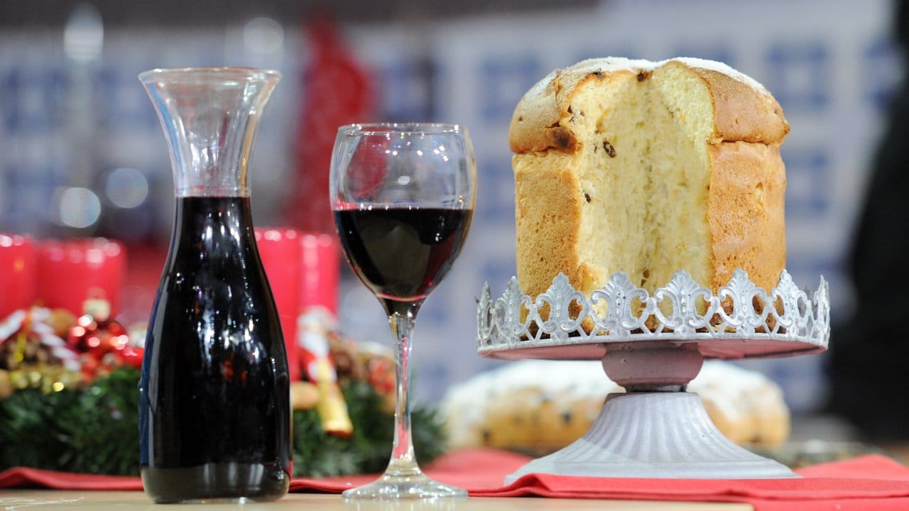 Das italienische Weihnachtsgebäck Panettone und ein Glas und eine Karaffe mit Rotwein.