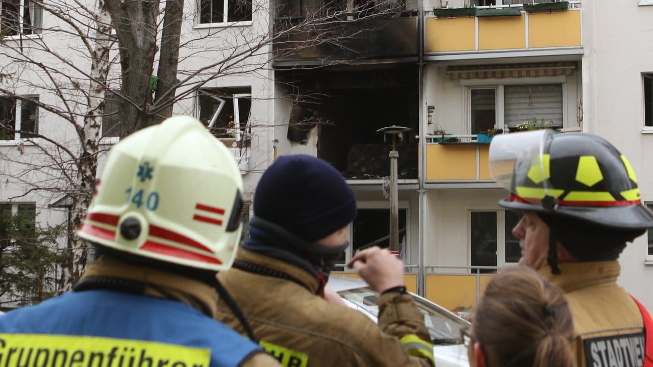 Einsatzkräfte stehen nach der Explosion vor dem Mehrfamilienhaus.