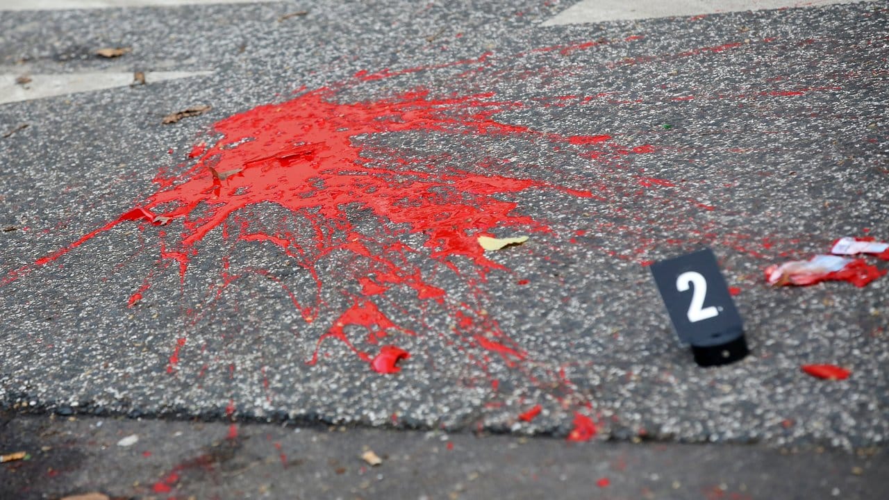 Farbe und Glasscherben liegen auf einer Straße hinter einer Polizeiabsperrung. Farbe und Glasscherben liegen auf einer Straße hinter einer Polizeiabsperrung.
