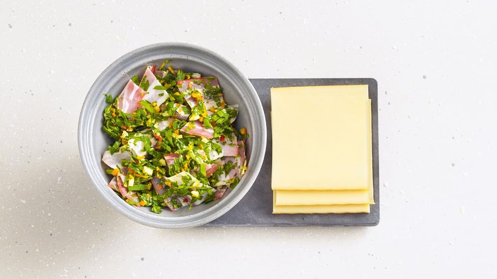 Bereits vorbereitete Pfännchen helfen unentschlossenen Gästen – wie dieses Chili-Speck-Pfännchen mit Chilischote, Petersilie, Knoblauch, Orange, Räucherspeck und Olivenöl.