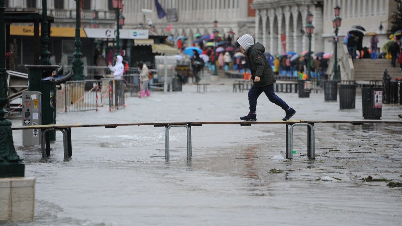 Das Wasser in Venedig steigt wieder: Ein Junge geht auf einem Steg über den überfluteten Markusplatz.