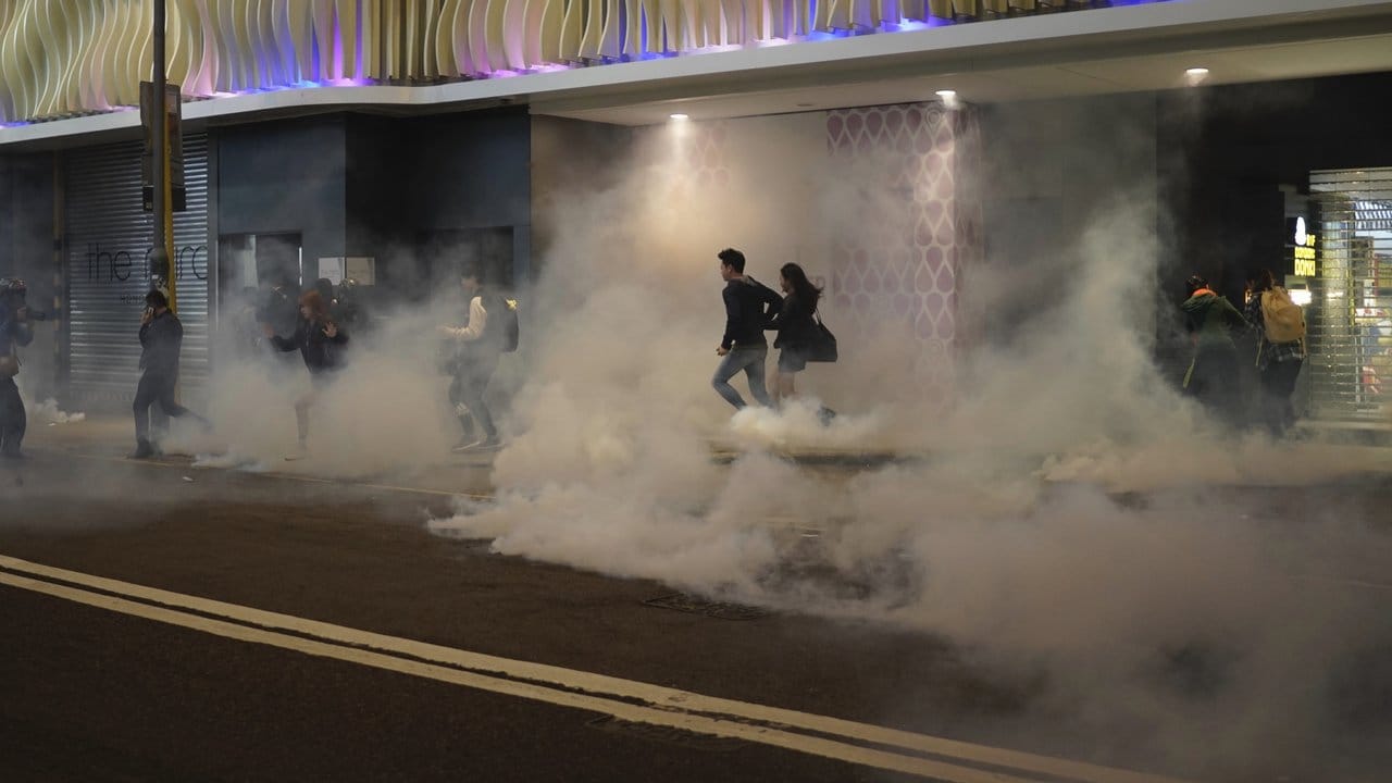 Anwohner flüchten auf einer Straße vor Wolken von Tränengas.