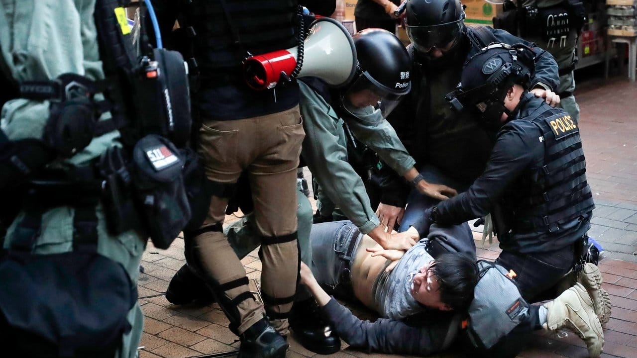 Bereitschaftspolizisten reißen einen Demonstranten zu Boden.