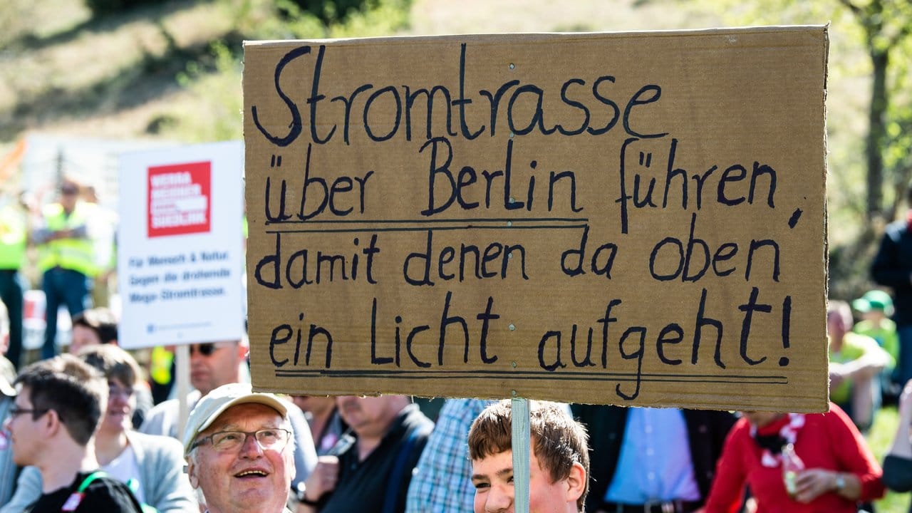 Teilnehmer mit Flaggen und Transparenten demonstrieren am Fuße der Brandenburg in Thüringen gegen die geplante Suedlink-Stromtrasse.