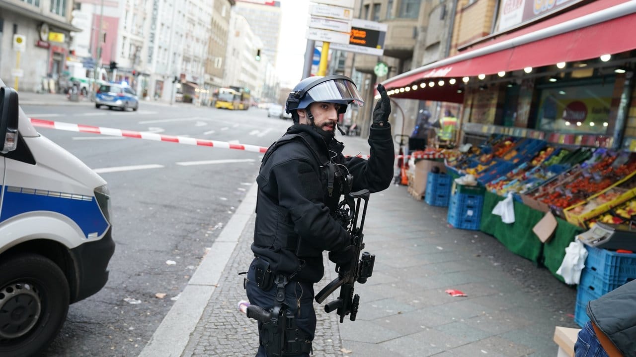 Ein Polizist in Schutzausrüstung weist Passanten an, sich in Sicherheit zu bringen. Ein Polizist in Schutzausrüstung weist Passanten an, sich in Sicherheit zu bringen.