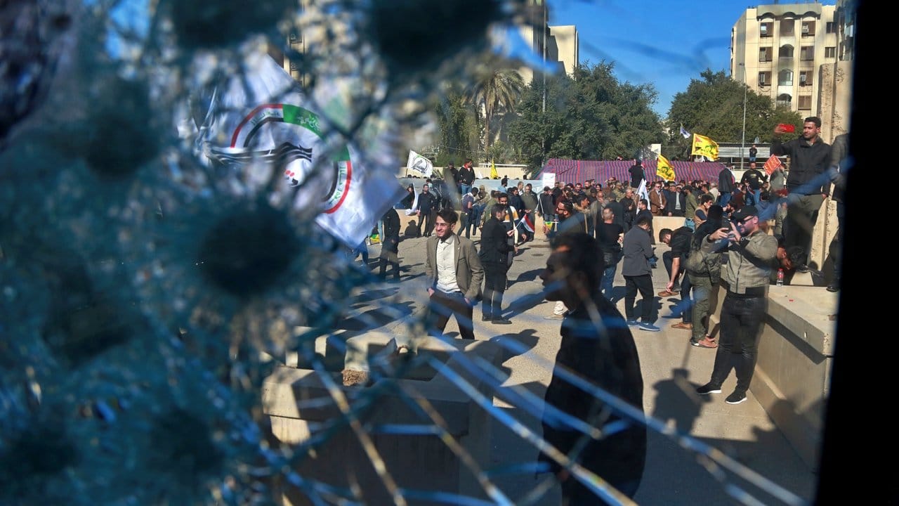 Demonstranten sind durch ein beschädigtes Fenster eines Kontrollpunktes der US-Botschaft zu sehen.