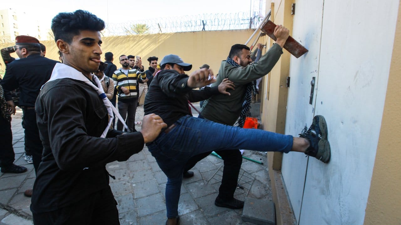 Mit Tritten versuchen Demonstranten, die Tür der US-Botschaft aufzutreten.