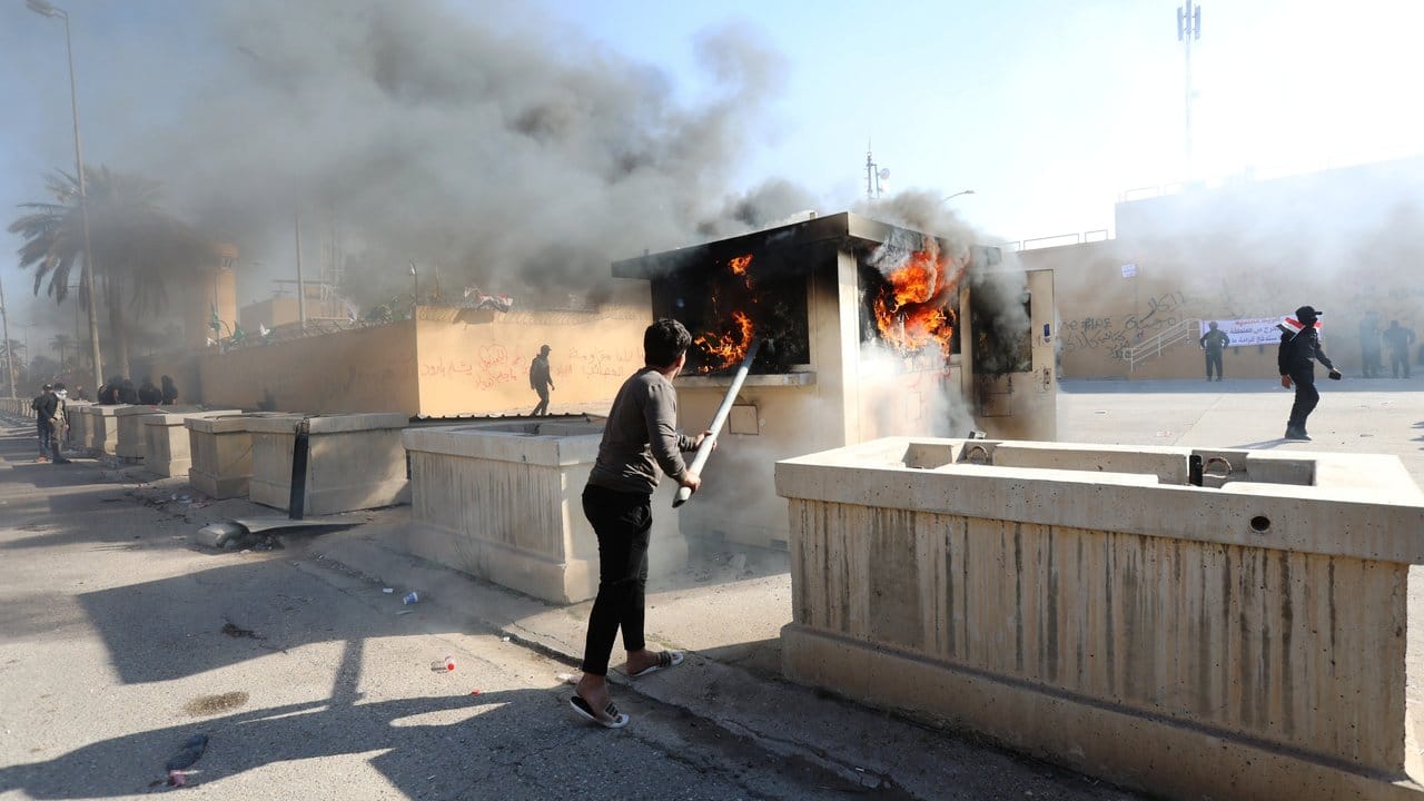 Ein Demonstrant schürt vor der Botschaft der Vereinigten Staaten in Bagdad ein Feuer.