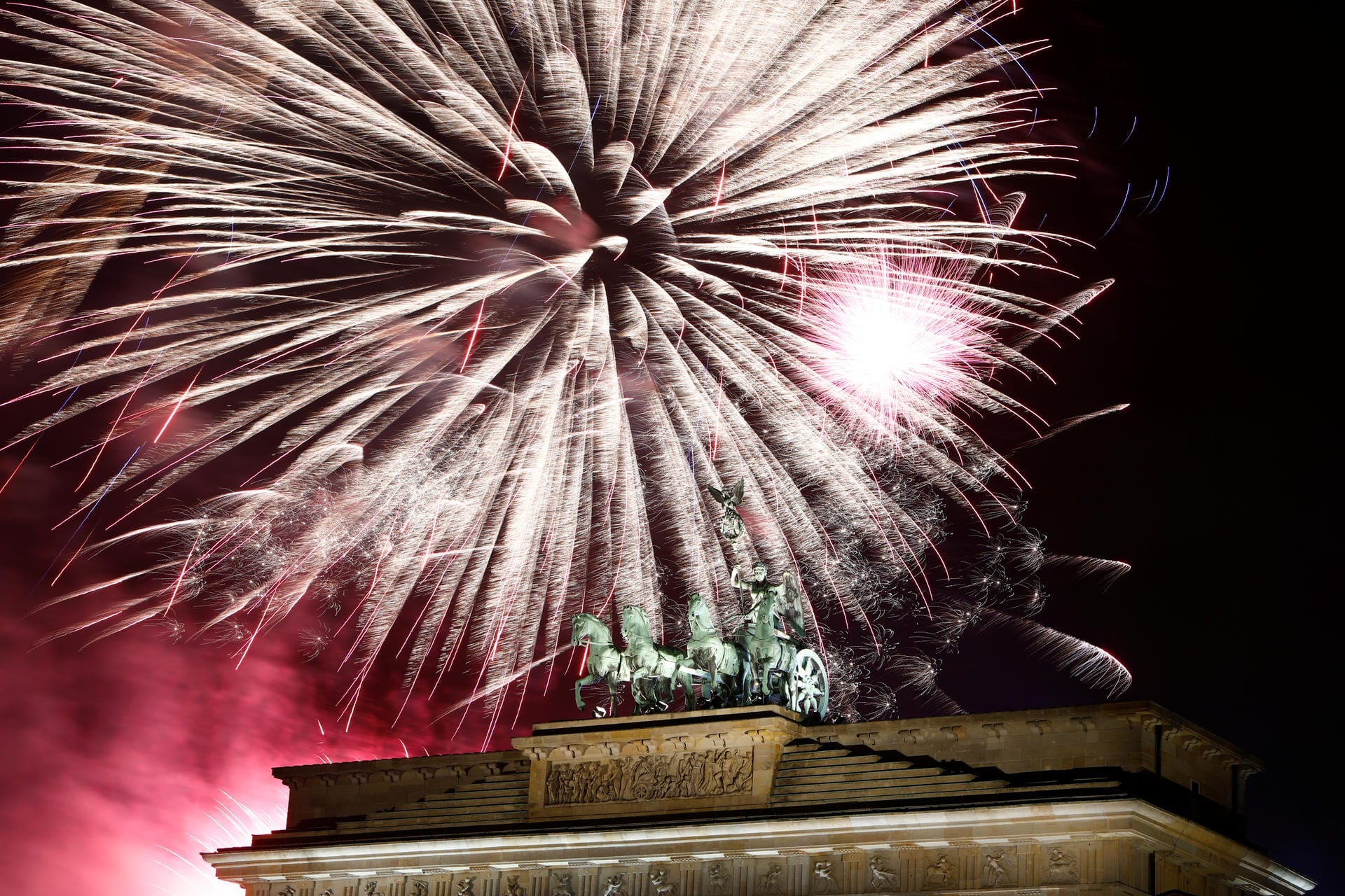 Brandenburg Tor in Berlin: Der Himmel ist erleuchtet von Feuerwerk.