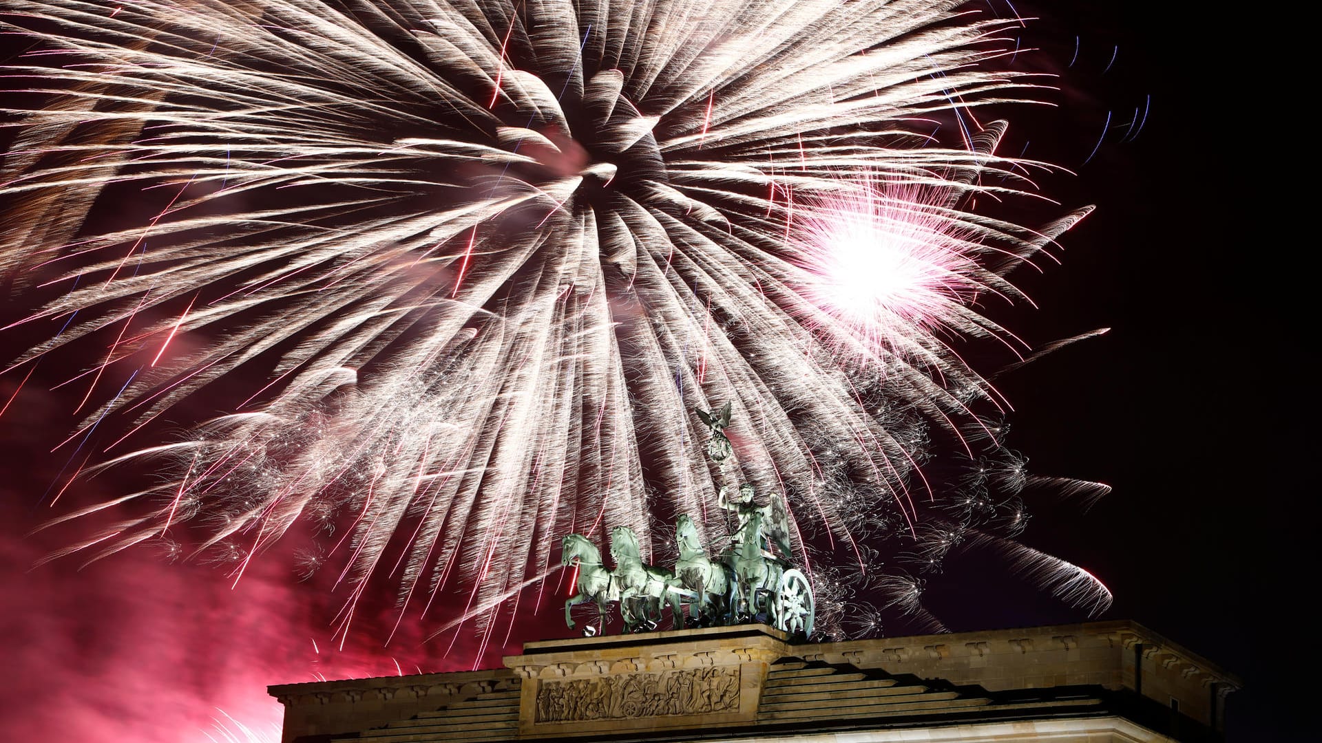 Brandenburg Tor in Berlin: Der Himmel ist erleuchtet von Feuerwerk.