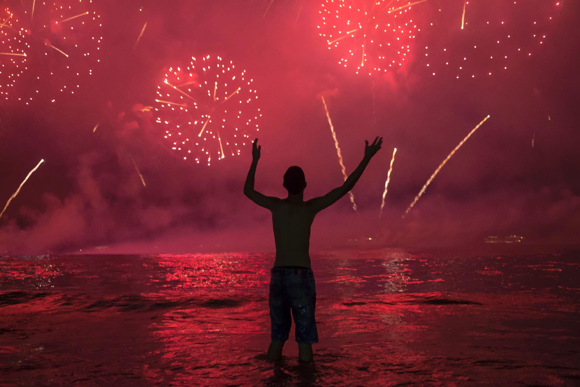 Rio De Janeiro: Ein Mann steht bei den Neujahrsfeierlichkeiten im Wasser am Copacabana Beach und betrachtet das Feuerwerk.