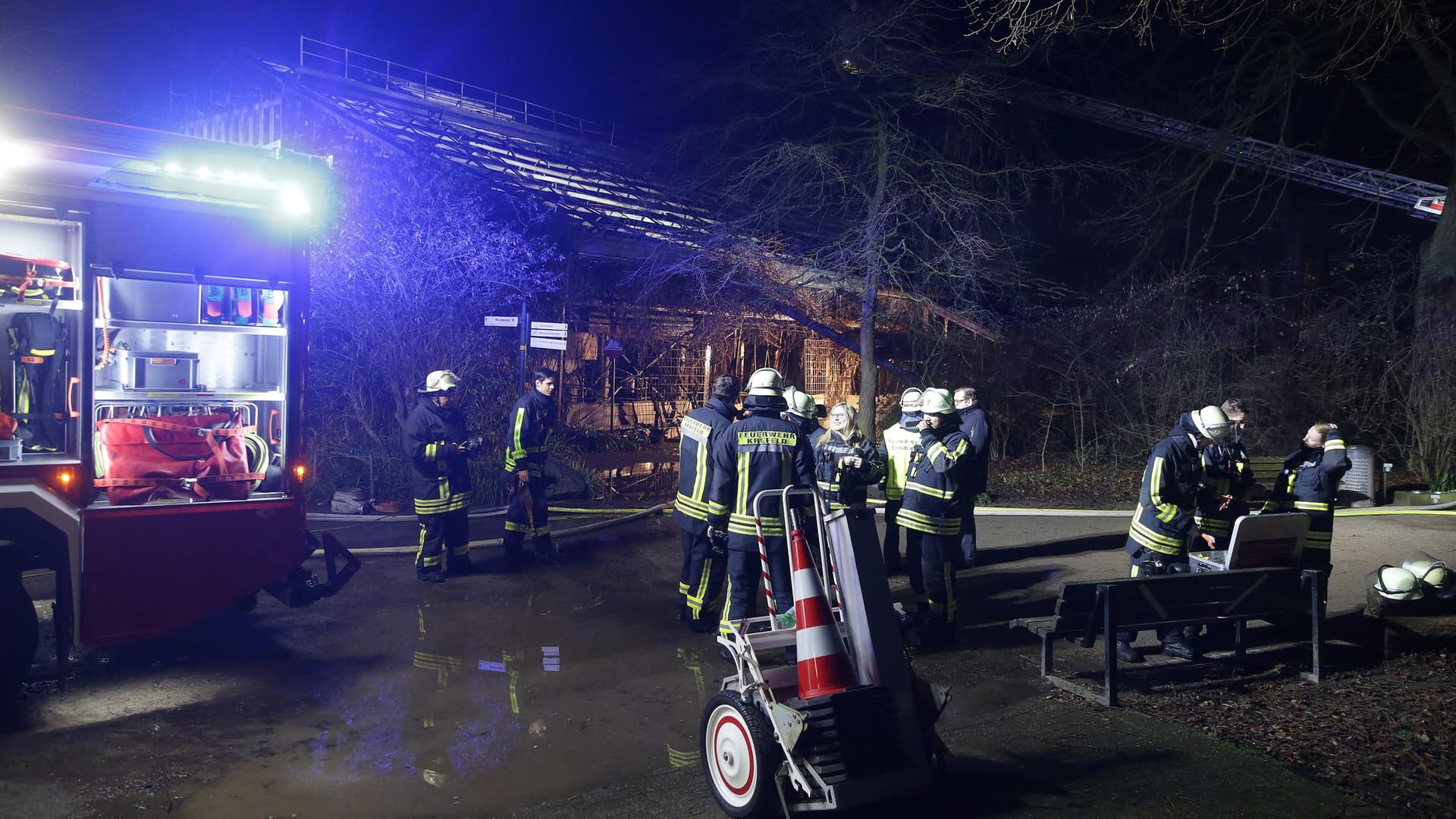 Feuerwehrleute stehen nach den Löscharbeiten vor dem Gebäude im Krefelder Zoo.