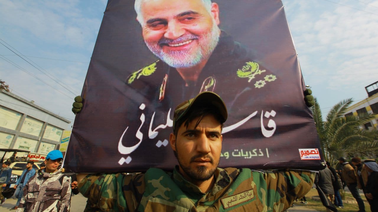 Beim Trauerzug in Bagdad hält ein Mann ein Bild Soleimanis.