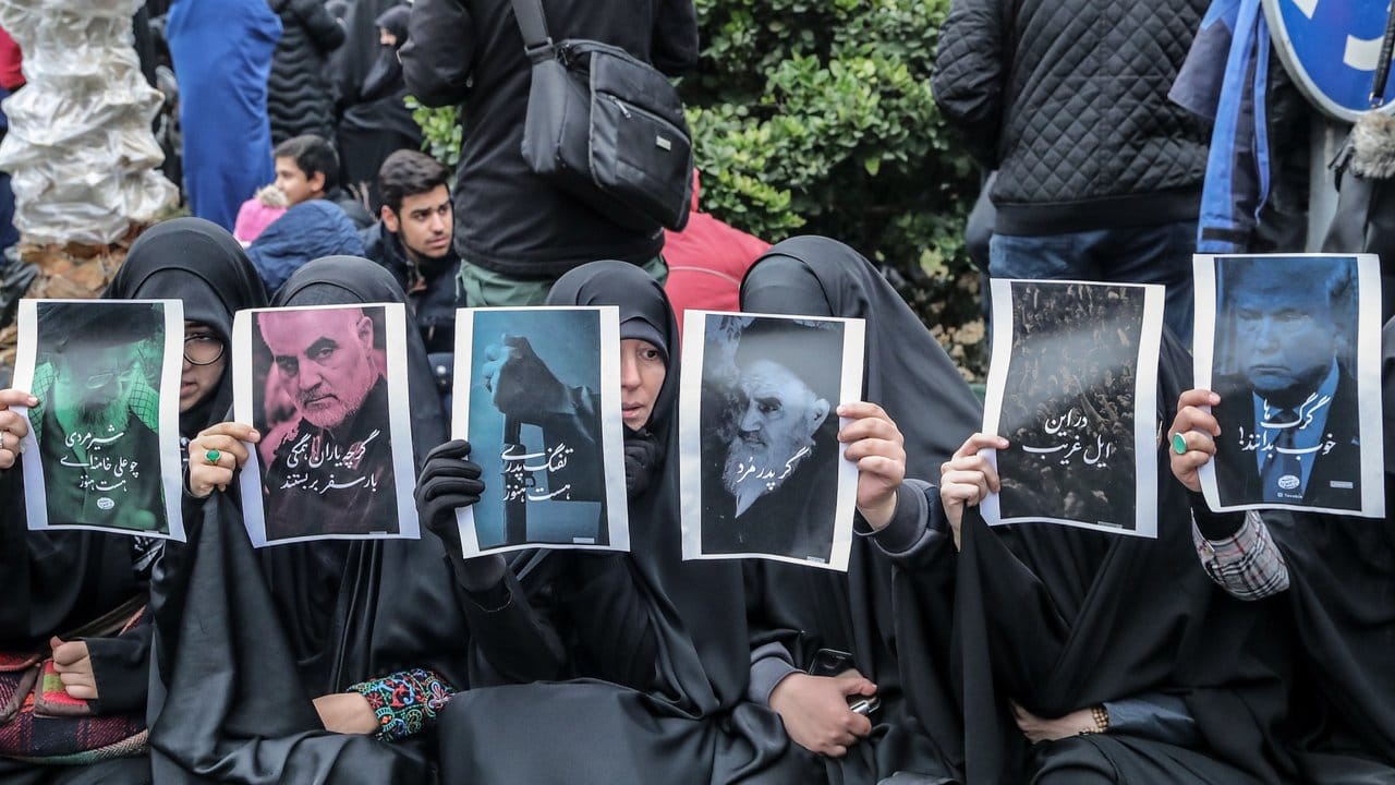 Iranische Frauen halten heim Trauerzug in Teheran Fotos hoch, auf denen unter anderen Ghassem Soleimani, Ruhollah Chomeini und Donald Trump abgebildet sind.
