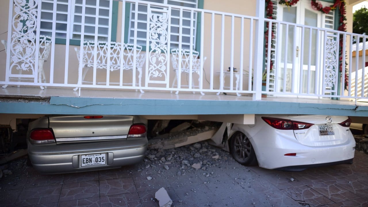 Zerstörte Autos stehen unter einem Haus, das nach einem Erdbeben teilweise eingestürzt ist.