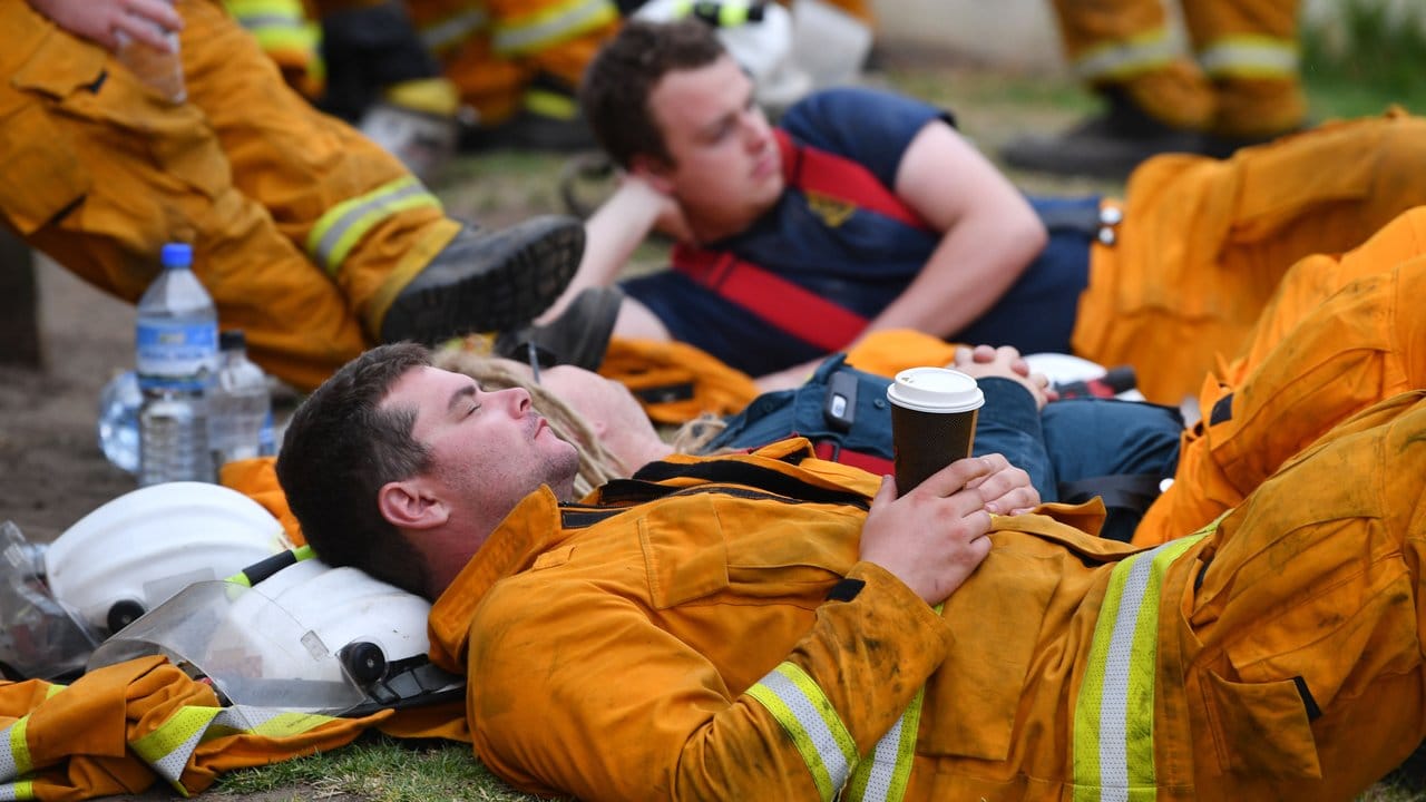 Erschöpfte Feuerwehrleute ruhen sich während eines Einsatzes gegen Buschbrände bei Adelaide aus.