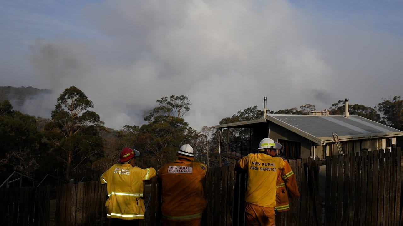 Feuerwehrmänner beobachten aufsteigende Rauchwolken eines Buschfeuers bei Penrose südlich von Sydney.