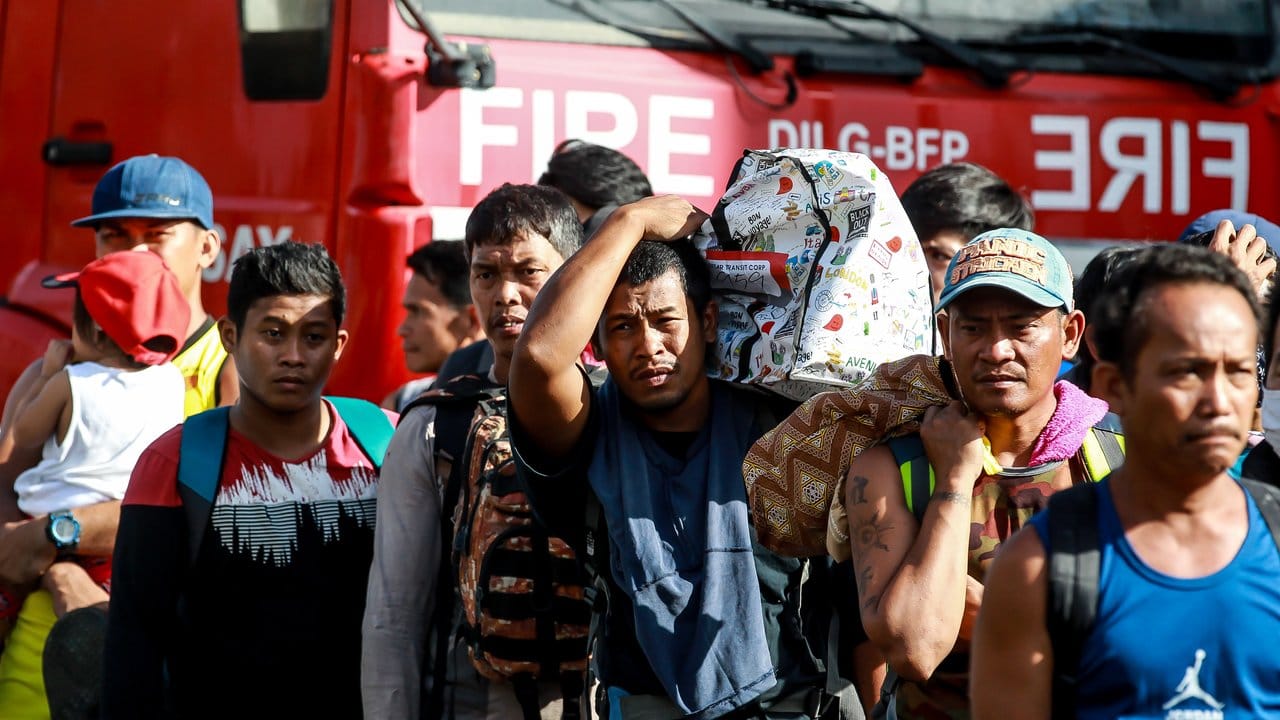 Bewohner der Stadt Batangas warten auf ein Militärfahrzeug, das sie zu einem Evakuierungszentrum bringen soll.