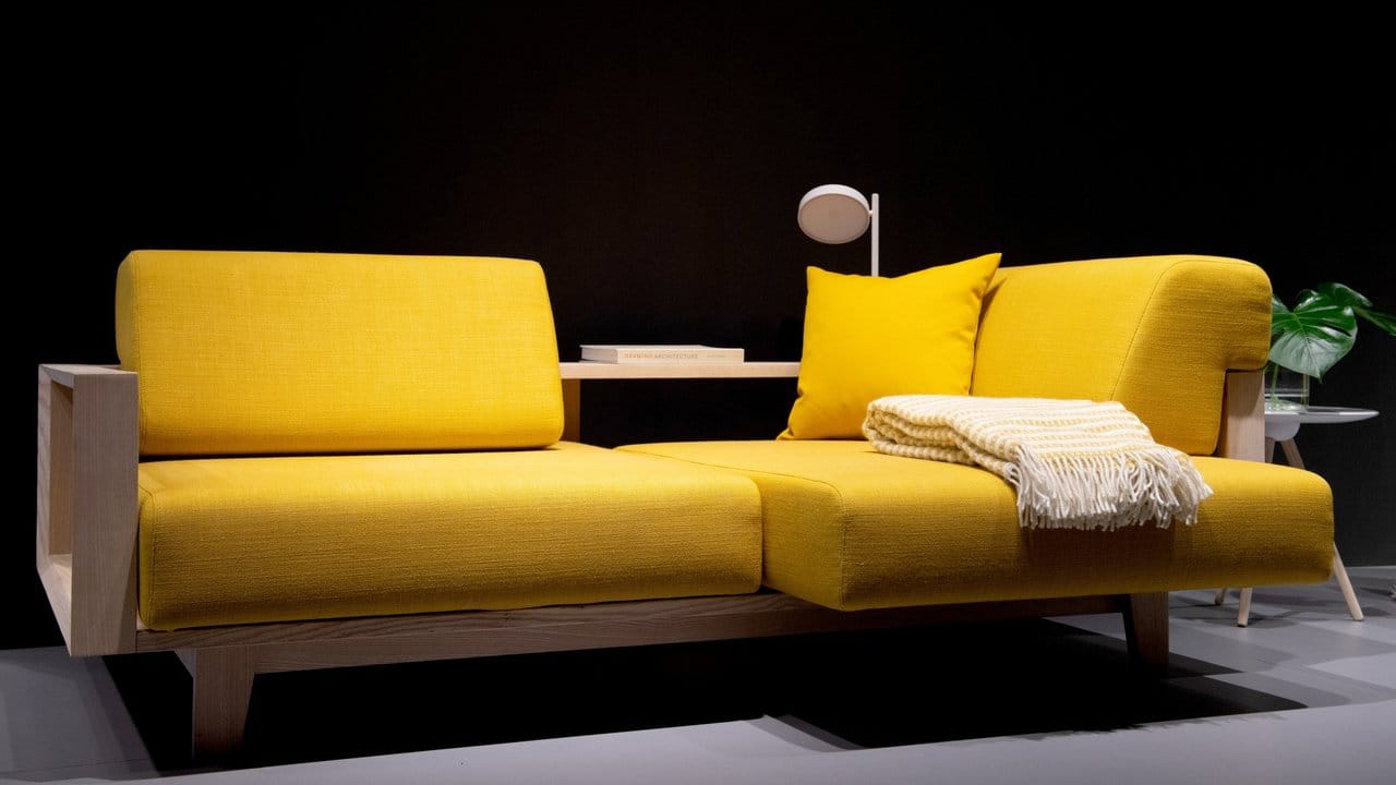 Der Hersteller Softline legt ein sonnengelbes Kissen auf ein nur minimal abschattiertes gelbes Sofa.