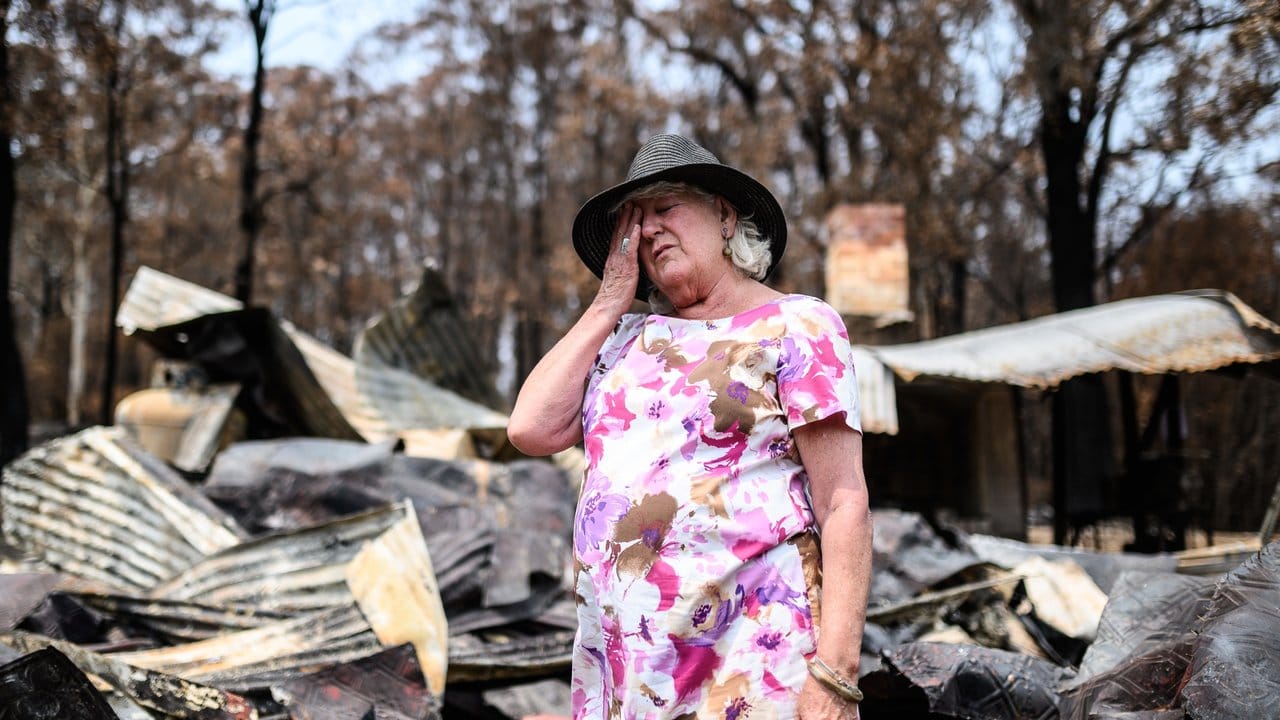 Eine Frau steht im Ort Mogo vor den Überresten ihres Geschäfts, das an Silvester abgebrannt ist.
