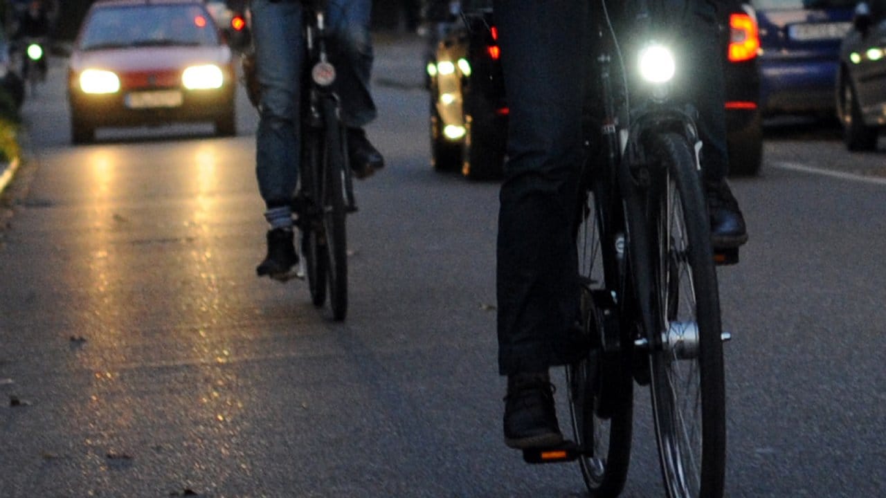 Ein Radfahrer ohne Licht fährt hinter einem Fahrradfahrer, der sein Licht eingeschaltet hat.
