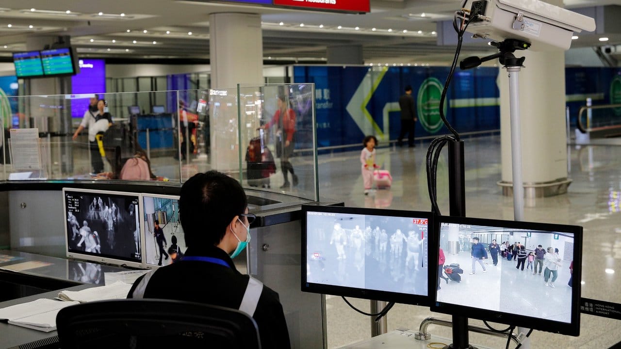 Ein Beamter der Gesundheitsüberwachung überwacht am Flughafen von Hongkong mit Wärmebildkameras die Temperatur von Reisenden.