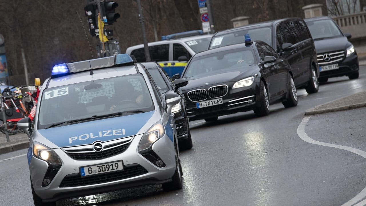Ein Fahrzeug-Konvoi fährt unter Polizeischutz am Brandenburger Tor vorbei.