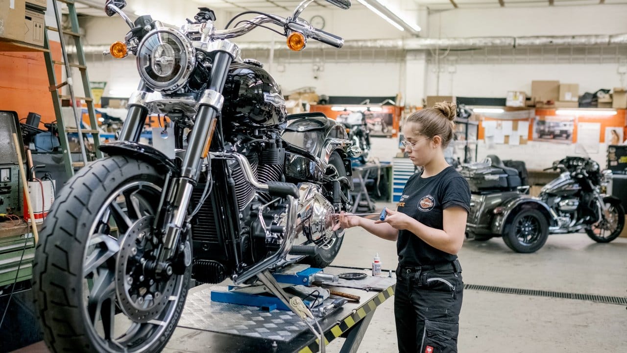 Maja Vukojevic tauscht die Chromblenden an einem Motorrad in einer Harley-Davidson-Werkstatt.