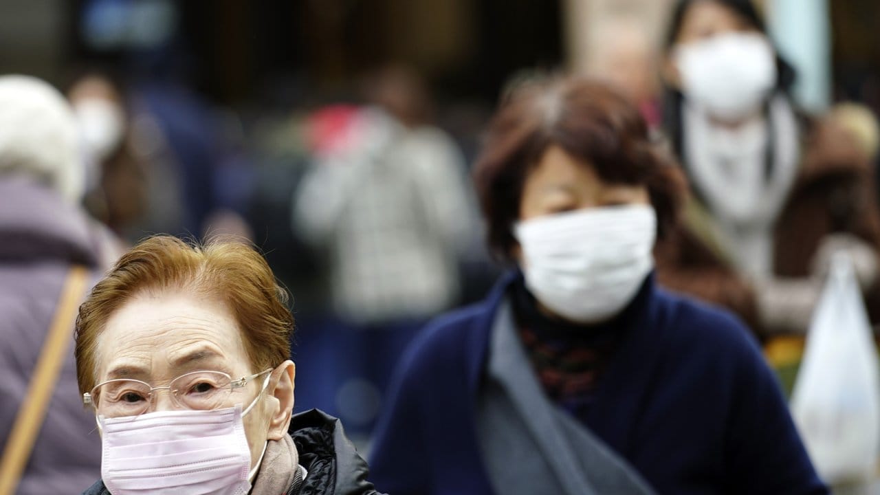 Fußgänger in Tokio tragen Schutzmasken.