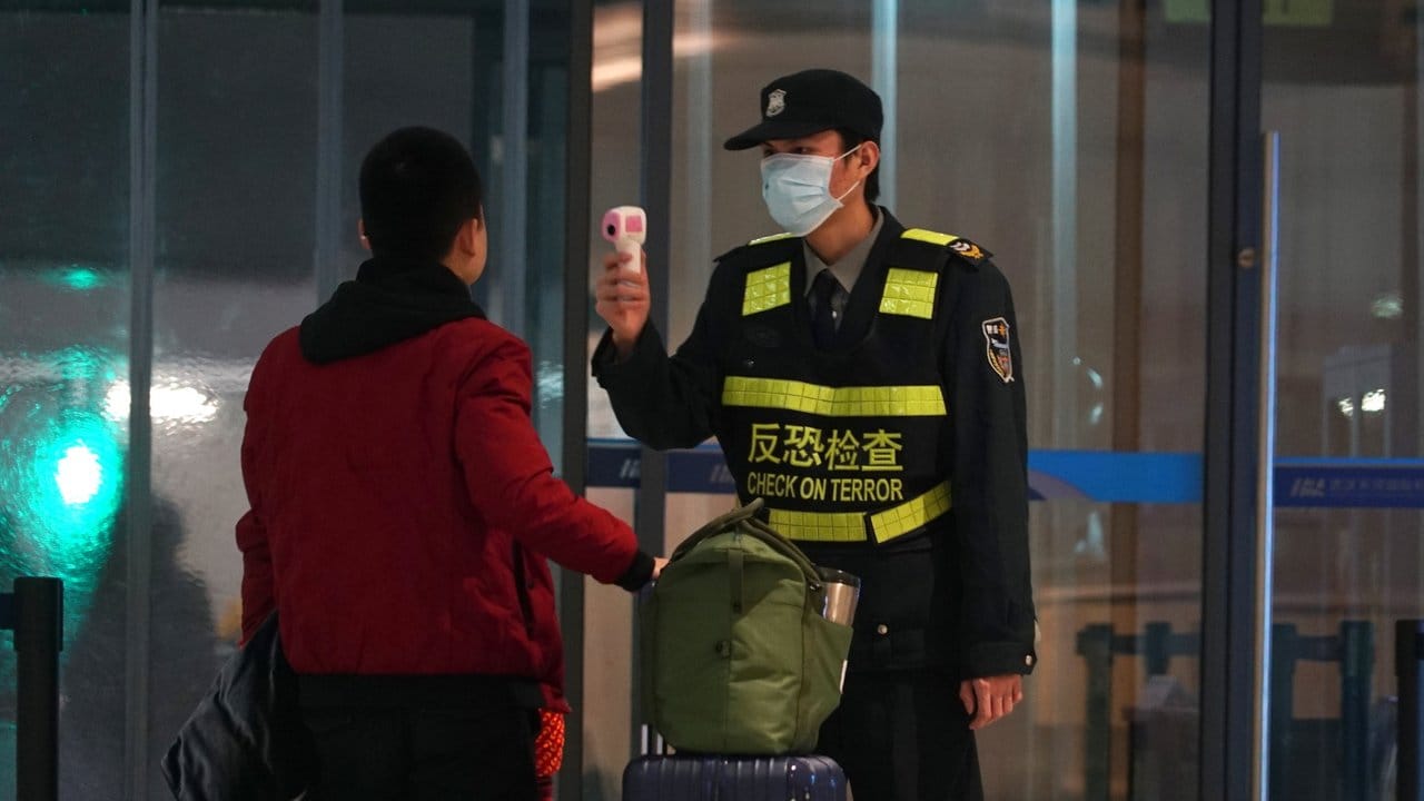 Schutzmaßnahme gegen die Verbreitung des Corona-Virus: Ein Beamter misst am Flughafen von Wuhan die Körpertemperatur von Reisenden.