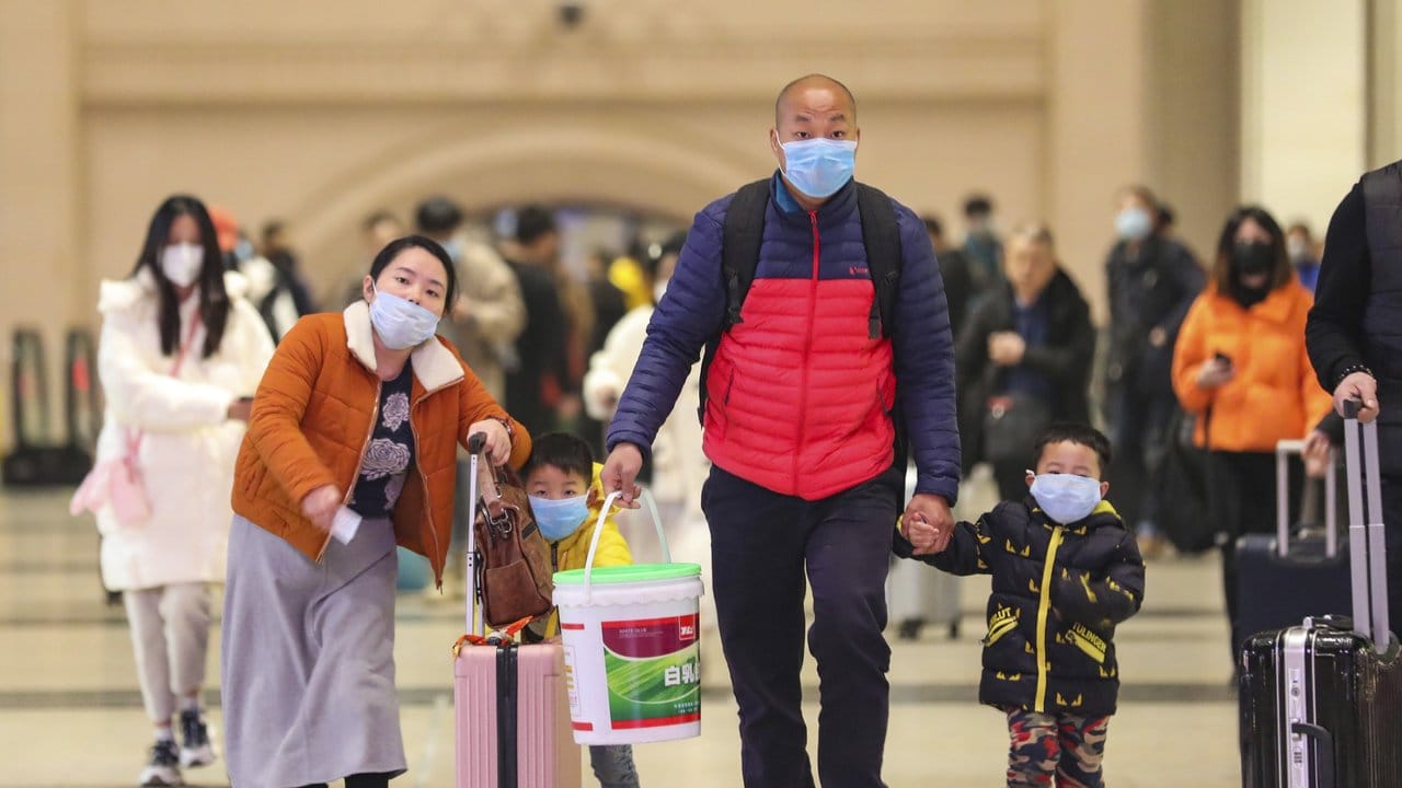 Reisende mit Atemschutzmasken gehen durch den Bahnhof Hankou in der chinesischen Stadt Wuhan. Reisende mit Atemschutzmasken gehen durch den Bahnhof Hankou in der chinesischen Stadt Wuhan.